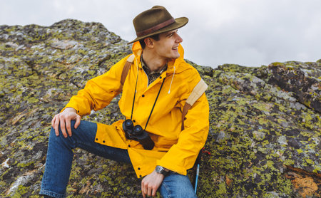 cheerful happy handsome hiker sitting on the big stones, enjoying amazing nature. close up photo