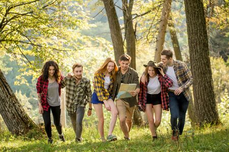 positive young tourists walking with a map in the forest, full length photo. travel, adventure, peopleの写真素材