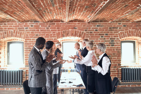 Colleagues smile, applaud, shake hands in honor of successfully closed deal