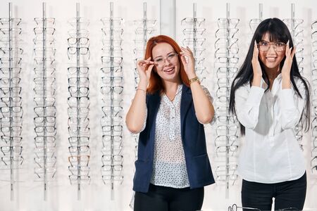 positive cheerful girls having fun at optics. close up photo. copy space. girls touching glasses and posing to the cameraの写真素材