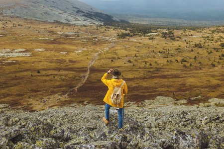 active h iker with backpack relaxing on top of a mountain and enjoying sunset. back view full length...