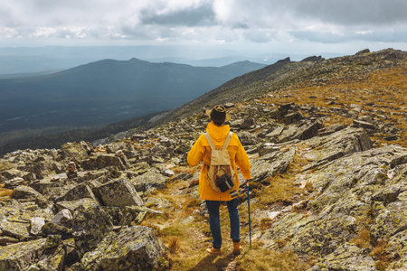 Young active motivated backpackers on top of a mountain enjoying valley view, full length back view...