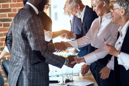 Group of businessmen at table in office shaking hands.の写真素材