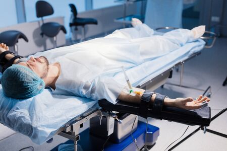 Male Patient with needle of the syringe is plugged into an intravenous catheter placed in the arm. Preparation for the surgery.の写真素材
