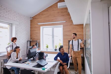 Young multi-ethnic team of business partners sit listen to successful speaking of experienced manの写真素材