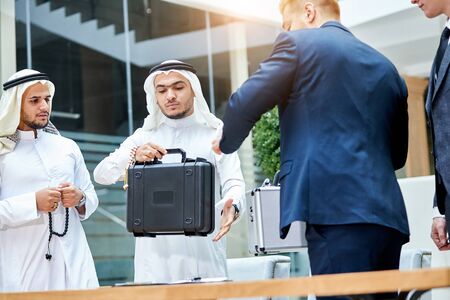 Arabic businessman make deal with caucasian businessman, get black case with technology of futureの写真素材