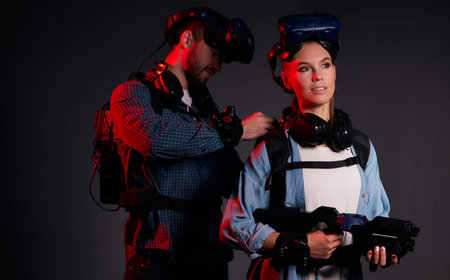 Young encouraged couple preapring for VR game, isolated on black background