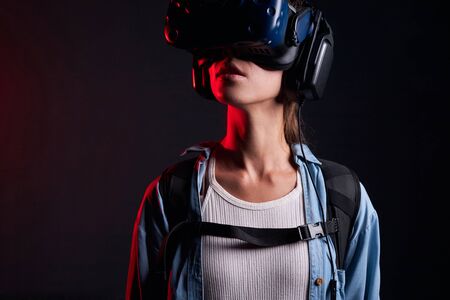 Portrait of young girl wearing VR device on eyes. Isolated over black background, UVの写真素材