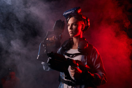 Attractive caucasian girl wearing special equipment, holding weapon for virtual game. Stand posing...