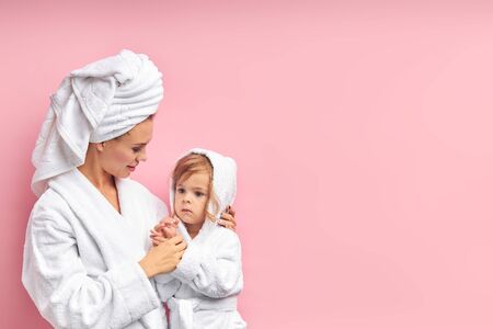 After taking bath, mother and her daughter in bathrobe and towel.isolated pink backgroundの写真素材