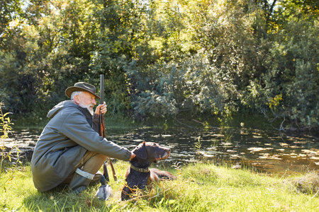 Have rest before hunting. Hunter man on lake, holding rifle