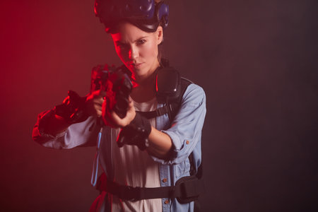 Beautiful caucasian female aimed her gun on camera, ready to shoot. Isolated smoky background