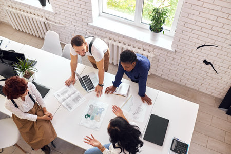Business team consisted of multiethnic people, gathered in office to discuss new project