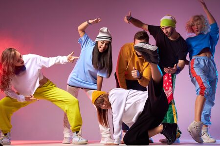 Hip hop battle in spacious dance hall, young people dancing break dance, pretty sportive girl in white hoodie and black loose pants showing street dance movieの写真素材