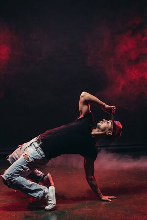 athletic male dancing street dance isolated over smoky background, stylish modern type of danceの写真素材