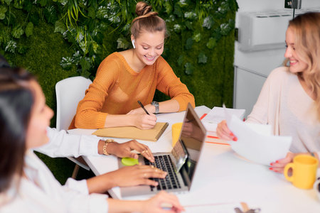Hold meeting for developing, building business strategy. Young women in casual wear gathered in...