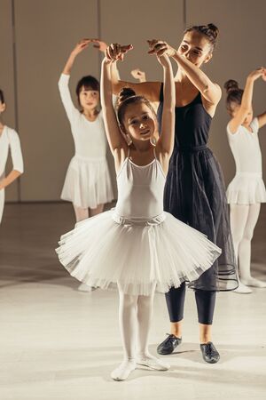 little girls practice in ballet class with young female teacher, wearing special tutu suits, performing ballet danceの写真素材