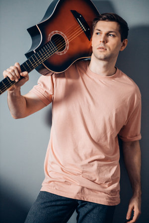 handsome caucasian guy wearing casual t-shirt posing at camera, looking side indoors