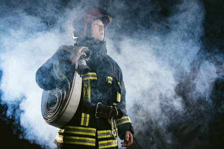 young fire fighter holding rope in hands ready to save and protect from fire