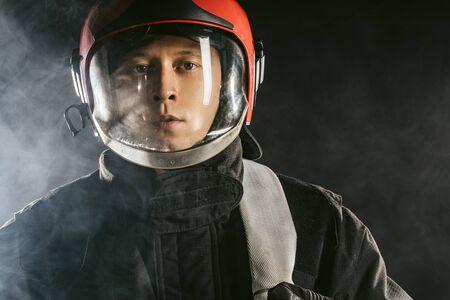 portrait of confident handsome fireman in helmet and uniform, serious fire fighter protect from fire. safety conceptの写真素材