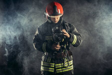 fireman or firefighter stand in smoke, professional worker of fire station in uniform, in helmetの写真素材