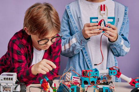 caucasian friends kids studying engineering, robotics, try to assemble robots, complex constructions...