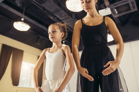 doing practice and training ballet dance with coach teacher woman in tutu skirt, teaching little...