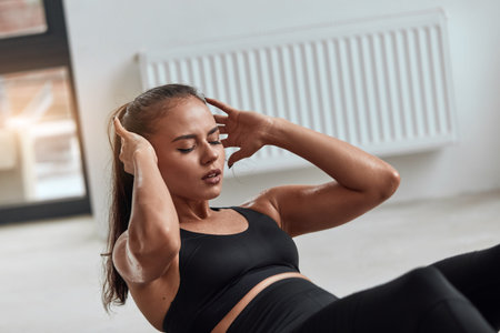 Sporty brunette with closed eyes in gym pumping, exercising. Black sportswear. Healthy lifestyle...