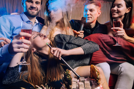 young ladies and guys chilling and rocking in karaoke bar, spend day-off in karaoke together with friends, enjoy time in clubの写真素材