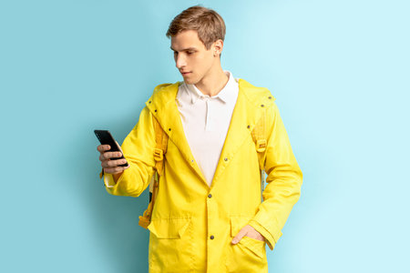 fast, express delivery by young caucasian man isolated over blue background, look at smartphone,...