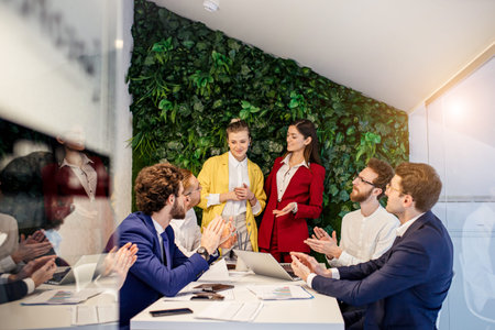 young enthusiastic business people gathered in office, wearing formal wear, diverse people discuss...
