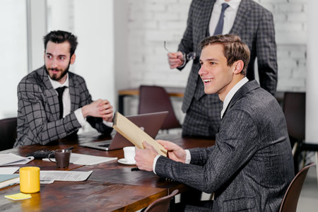 young men in suits gathered in business meeting for discussing together business strategies, developing new strategy for future year or monthの写真素材