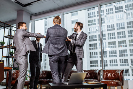 rear viw on happy business coworking of men in office, laugh and smile together, celebrating their...