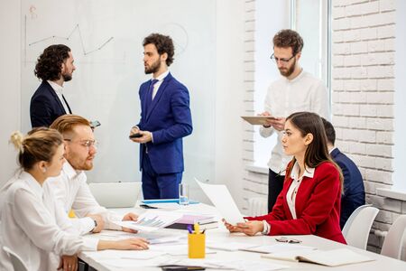 young diverse caucasian people hold business meeting in office, everyone in formal wear, have conversation and discussion of business project and deadlinesの写真素材
