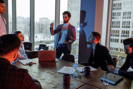 business crew coworking in modern office with neon lights. handsome guys in formal suits work as...