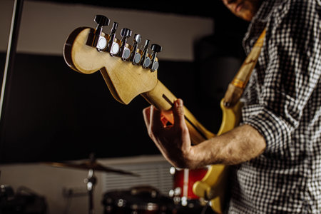close-up photo of young man holding electric guitar, talented musician perform music in studio,...