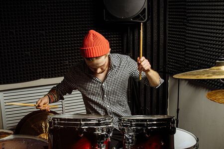 young caucasian talented man emotionally play the drums, he loves and enjoy playing on instruments. drummer playing on drum kit. drum player kick drum plateの写真素材