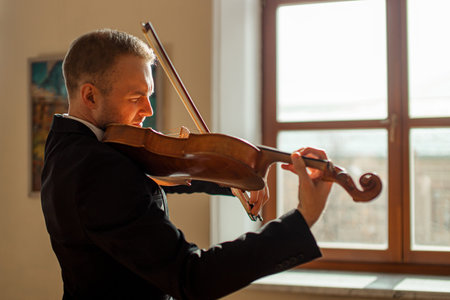 young talented professional man gracefully play violin, handsome musician in formal elegant suit...