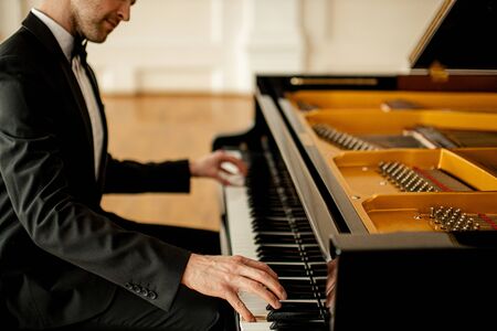 professional caucasian pianist practicing before concert on a stage. handsome guy perform classical musicの写真素材