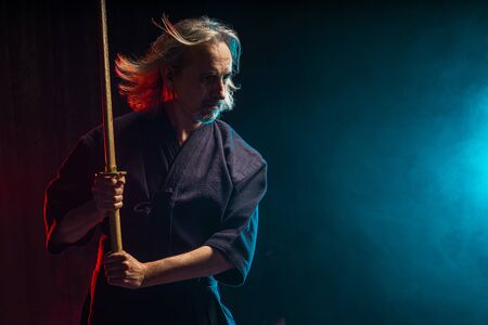 confident strong mature kendo warrior with shinai in hands, preparing for kendo competitions, fighting. isolated smoky spaceの写真素材