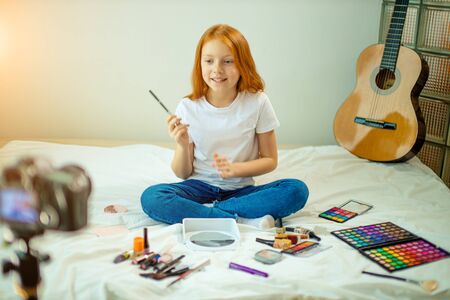 young beautiful caucasian child blogger show her new decorative cosmetics at camera, share opinion with subscribers. blog, vlog conceptの写真素材