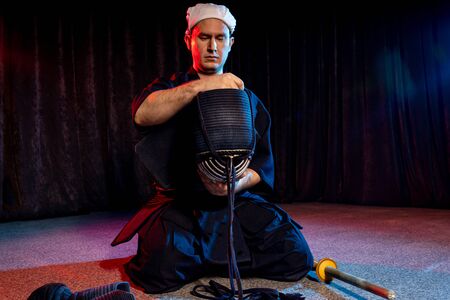 caucasian kendo fighter sit on the floor before fighting, wearing special kendo dress and using all equipment, bamboo sword shinai. japanese martial art as hobbyの写真素材