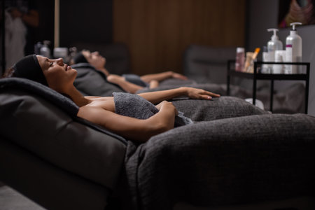 side view on young relaxed women lying on bed after face lift procedure, good-looking female takes...
