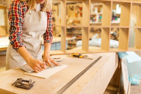 young female woodworker make drawings before drilling and sawing, handmade wooden furniture, handicraft conceptの写真素材