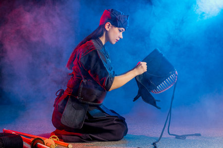 cuacasian kendo female wearing protective helmet on head before practicing fight. traditional...