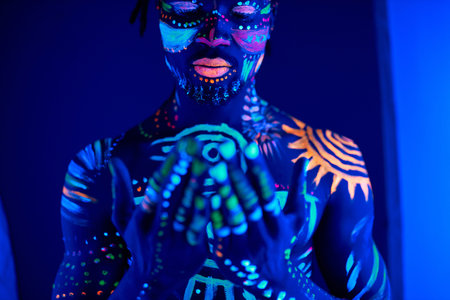 portrait of calm african man with fluorescent prints on skin praying for the best, stand in the pose of prayer. luminescence, fluorescence, body art conceptの写真素材