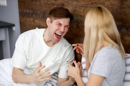 husband and wife do not understand each other, argue lying on bed, scream and try to explain and...