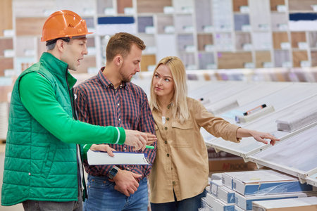 affable caucasian male warehouse worker consult and help to customers, show the best variant of...