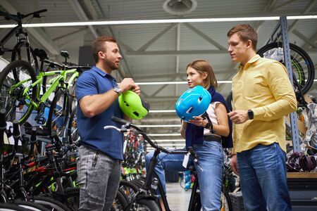 consultant give the most protective helmet to customers, woman want to buy sportive bicycle and helmet for it, ask for help by salesmanの写真素材