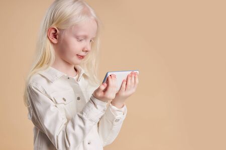 portrait of attractive caucasian albino girl with white smartphone, girl with breathtaking beauty use mobile phone. perfect color combinationの写真素材